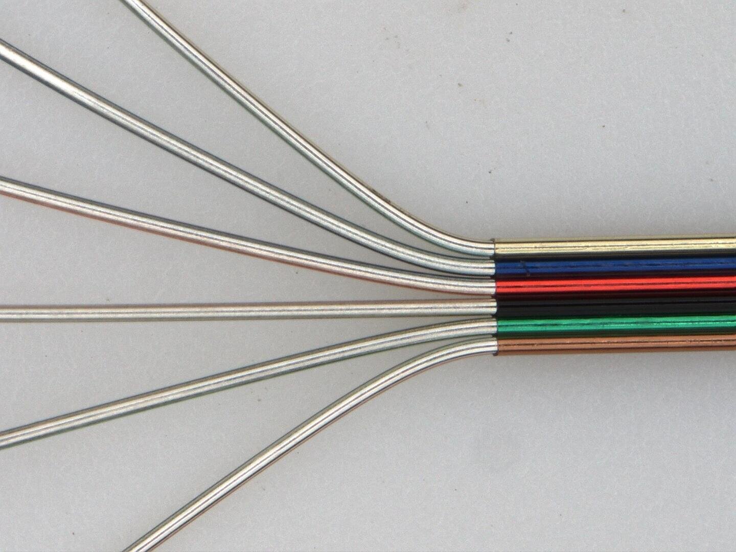 Six metallic wires, each with a colored stripe (black, blue, red, green, brown, and white), fan out from a single bundle against a plain, light background.