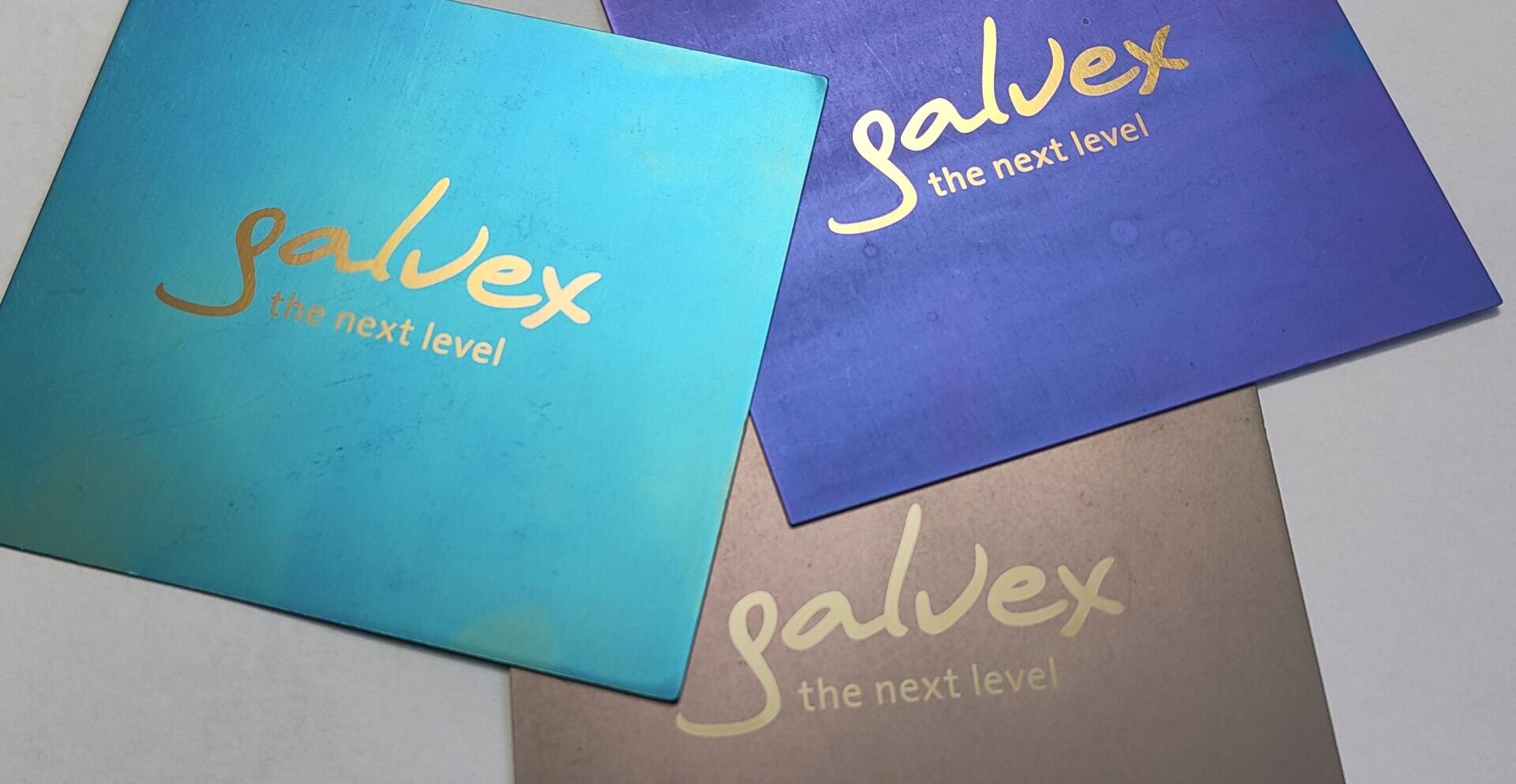 Drei quadratische Karten in den Farben Teal, Blau und Bronze, jede mit dem goldenen Text galvex the next level in einer handschriftlichen Schriftart, leicht überlappend auf einer hellen Oberfläche angeordnet.
