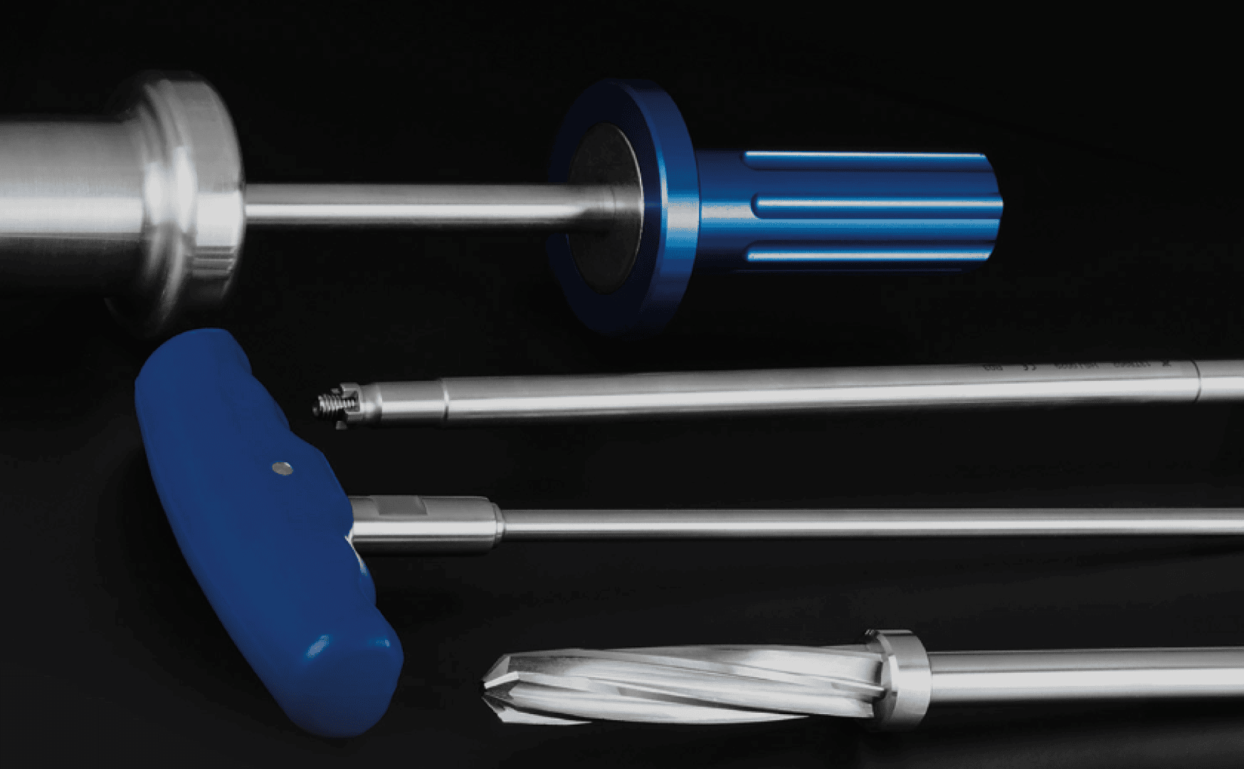 Four metallic orthopedic surgical tools with blue handles are arranged diagonally on a black background. The tools feature various shapes, including cylindrical, T-shaped, and spiral-ended designs.