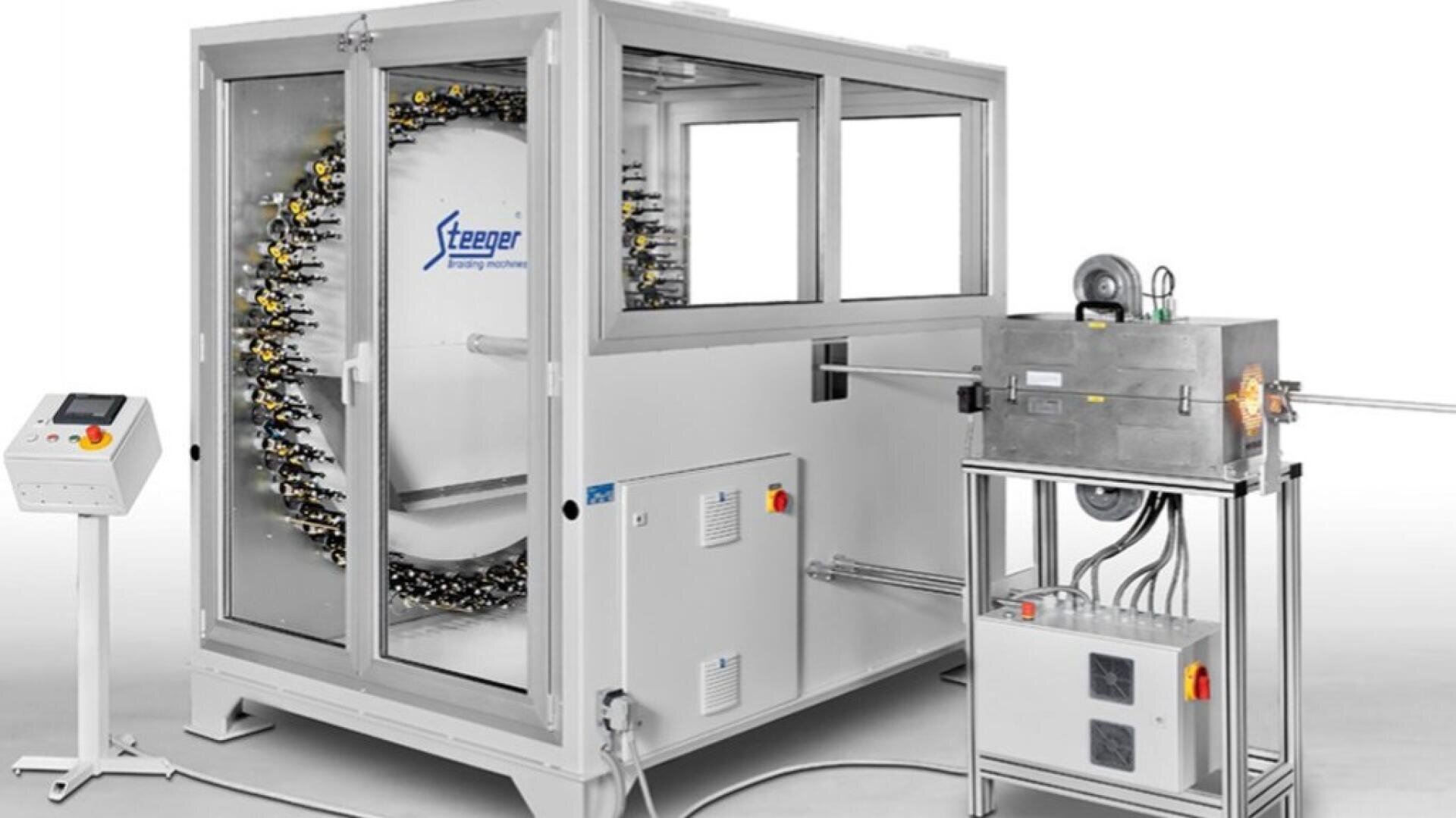 Eine moderne Industriemaschine mit einem großen kreisförmigen Array in einem Glasgehäuse mit der Aufschrift Steeger, das über Schläuche mit einer kleineren Metalleinheit auf einem Ständer verbunden ist, mit einem Bedienfeld in der Nähe.